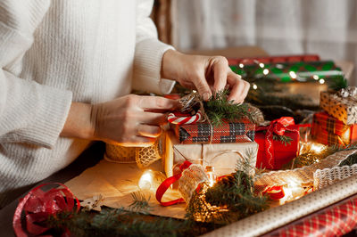 Women's hands decorate the box with the christmas gift. table with decor and materials for