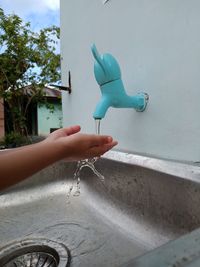 Cropped image of hand holding water from faucet