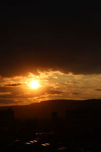 Silhouette cityscape against romantic sky at sunset