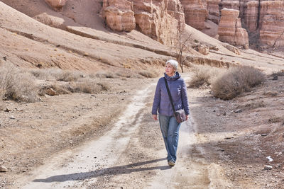 Senior caucasian woman tourist walking along charyn canyon, national natural park in kazakhstan.