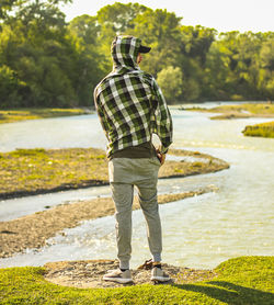 Rear view of man standing at riverbank