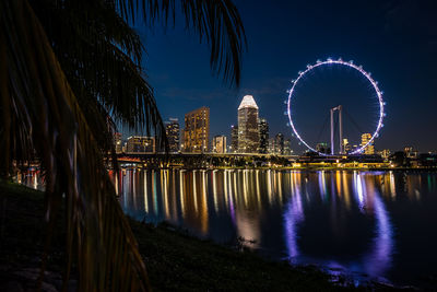 Illuminated bridge over river against sky at night