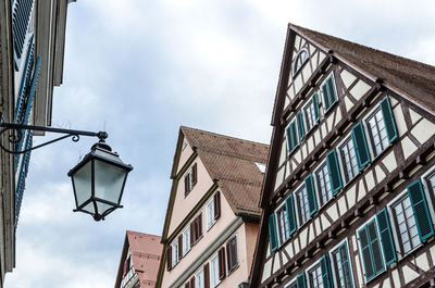 Low angle view of street light by building against sky