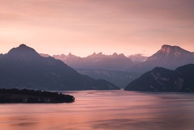 Scenic view of lake and mountains against sky during sunset