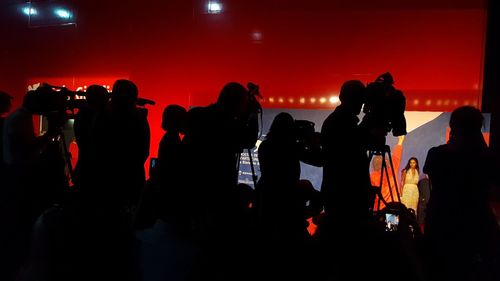 Silhouette people with television camera at studio