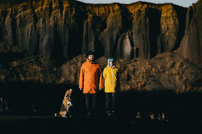 Rear view of a couple and a dog standing on rock