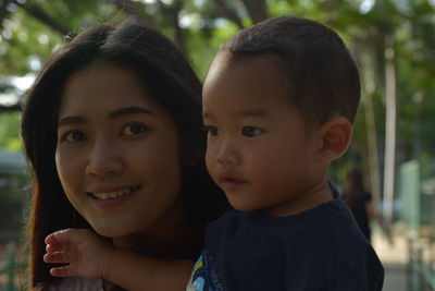 Close-up portrait of smiling mother with son in park