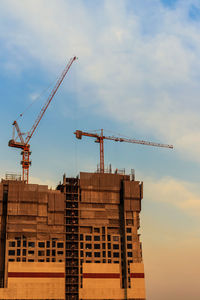 Cranes at construction site against sky