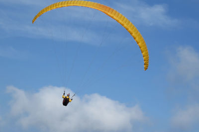 Low angle view of man paragliding against sky