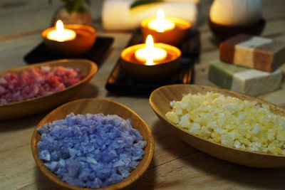 Lit tea lights and ingredients in bowls at spa