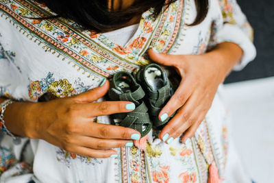 Midsection of pregnant woman holding baby booties