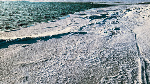 Aerial of frozen lake with patterns and snow drifts on the beach