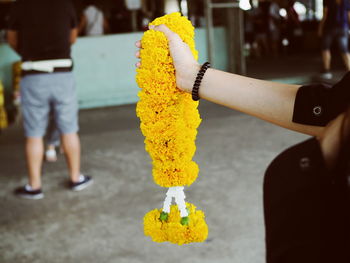 Midsection of person holding floral garland 
