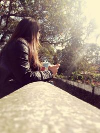 Side view of young woman sitting on tree