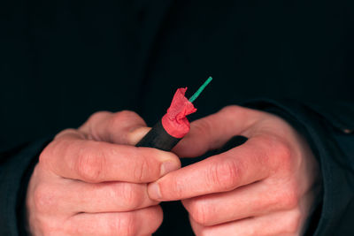 Close-up of hand holding red leaf against black background