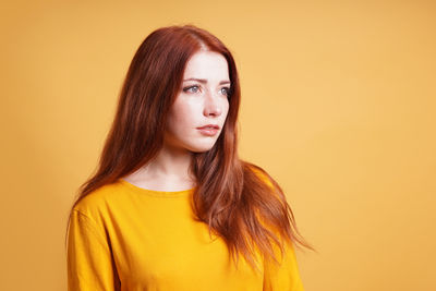 Portrait of young woman against yellow background