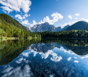 Reflection of cloudy sky with mountains and trees in lake