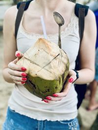 Midsection of woman drinking coconut milk while standing outdoors