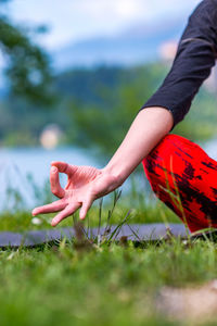 Midsection of young woman doing yoga on field