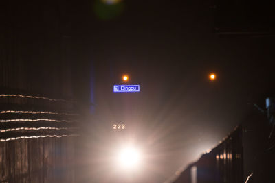 Low angle view of illuminated sign against sky at night