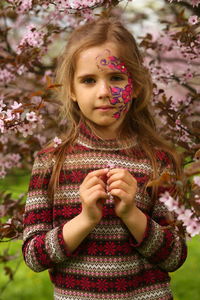 Spring portrait of a six year old girl standing under the blooming pink cherry tree