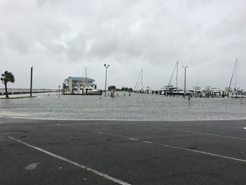 Sailboats on harbor by sea against sky