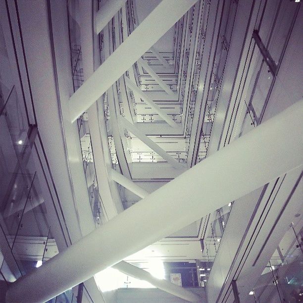 built structure, architecture, low angle view, indoors, railing, bridge - man made structure, glass - material, building exterior, sunlight, connection, modern, building, staircase, day, no people, metal, ceiling, window, city, steps