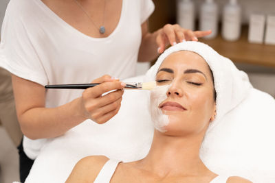 Beautician applying face mask to woman