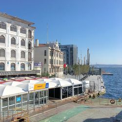 Built structure by sea against clear blue sky