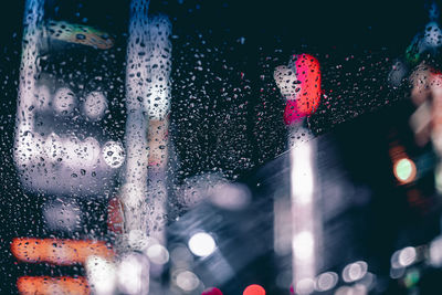 Raindrops on car windshield against illuminated buildings at night