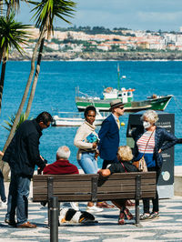 People sitting on seat by sea