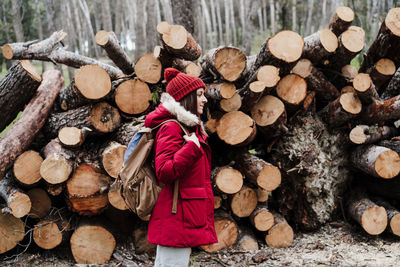 Woman standing against wooden logs