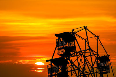 Silhouette cranes against orange sky