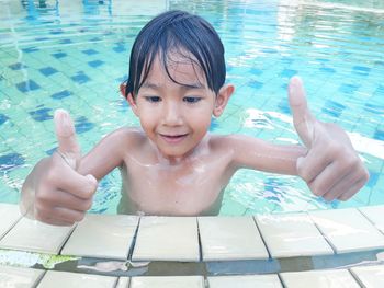 Smiling cute boy gesturing thumbs up in swimming pool