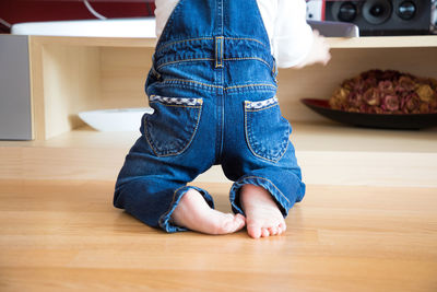 Low section of child kneeling on hardwood floor