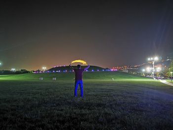 People standing on field against sky at night