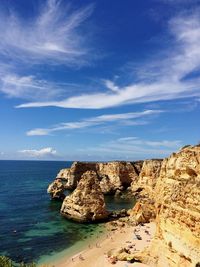 Rock formations by sea against blue sky