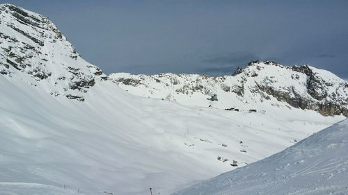 Scenic view of snow covered mountains against cloudy sky