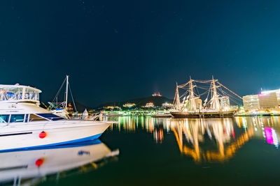 Boats moored on river against sky at night