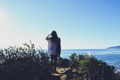 Man standing by sea against clear blue sky