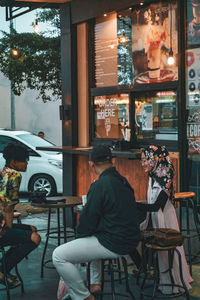 People sitting in restaurant by street in city