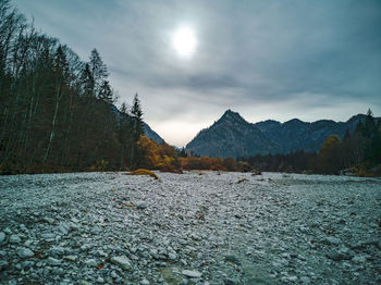 Scenic view of mountains on a river bed against the sun in the bavarian alps near ruhpolding