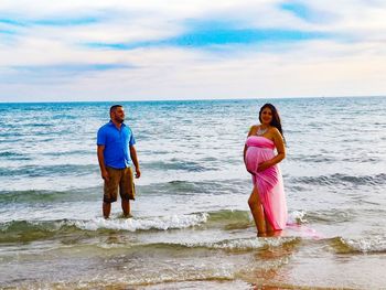 Full length of young woman standing at beach against sky