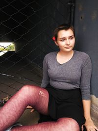 Portrait of young man sitting against wall