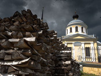 Close-up of wood stacked by built structure against sky