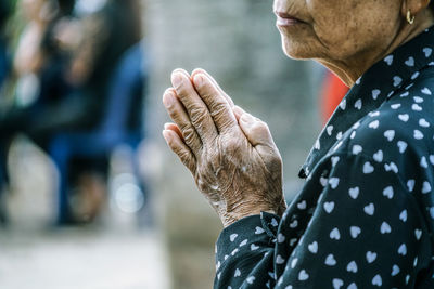 Midsection of senior woman with hands clasped praying at temple
