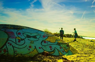 Graffiti on wall by footpath against sky