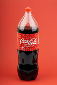 Close-up of glass bottle against red background