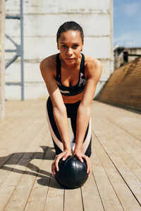 Portrait of young woman on ball while exercising on floorboard