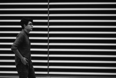 Side view of young man walking by corrugated iron